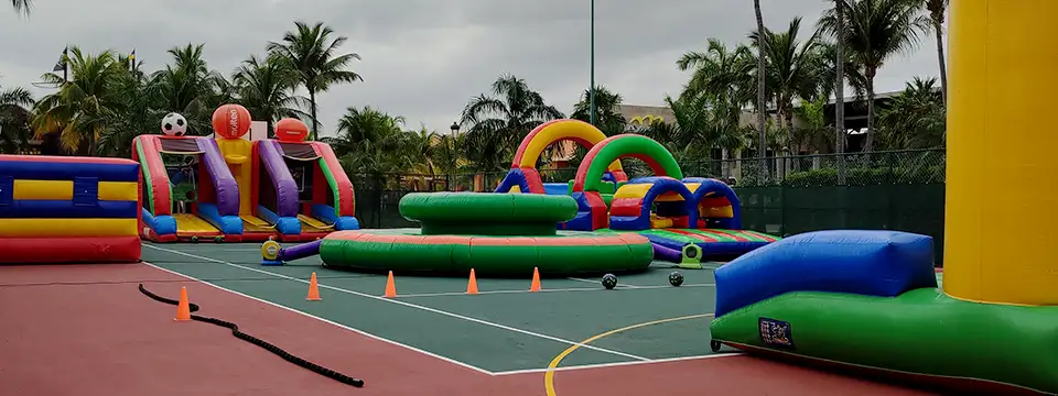 Estudiantes interactuando con inflables deportivos en la cancha de basquetball de su colegio.